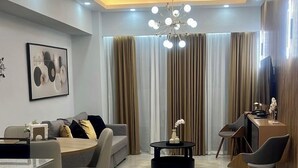 Una sala de estar moderna con un sofá, una mesa de comedor, sillas, una mesa baja y un televisor.