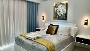 Un dormitorio moderno con una cama grande, un lámpara en el techo y un cuadro en la pared.