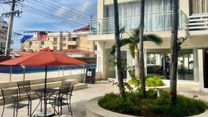 Un hotel con piscina, zona de estar al aire libre y palmeras.