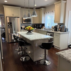 A modern kitchen with a central island, stainless steel appliances, and bar stools. - Stylish Central LA Retreat – Minutes from Museums & Stadiums for OlympicsI! (Los Angeles)
