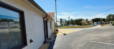 A building with a large window, a sidewalk, and a parking lot.
