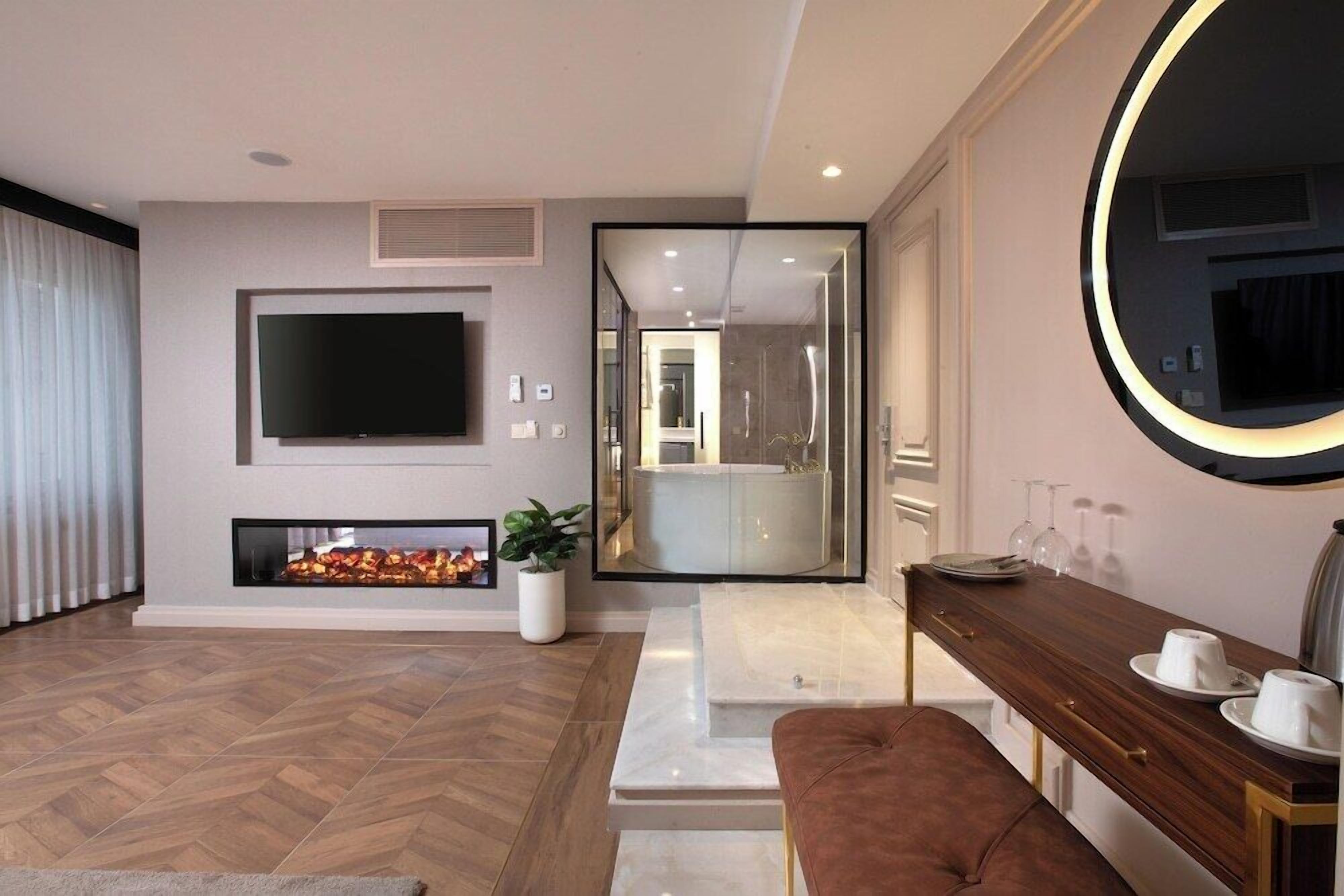 Uma sala de estar moderna com uma TV de tela plana, lareira e um espelho com moldura circular.
