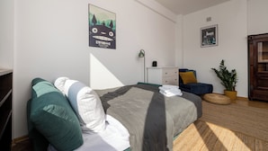 A neatly arranged bedroom with a bed, pillows, a bedside table, a lamp, a potted plant, and wall art. - Plac Wilsona Charming Apartment (Warszawa)