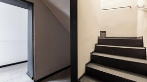 A modern staircase with a minimalist design, a glass door on the left, and a metal handrail on the right.