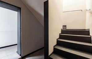 A modern staircase with a minimalist design, a glass door on the left, and a metal handrail on the right.