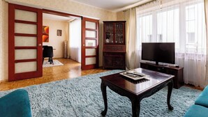 A living room with a wooden coffee table, a television, and a blue carpet.