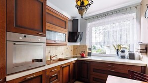 A kitchen with wooden cabinets, stainless steel appliances, a window with a view, and a dining area.