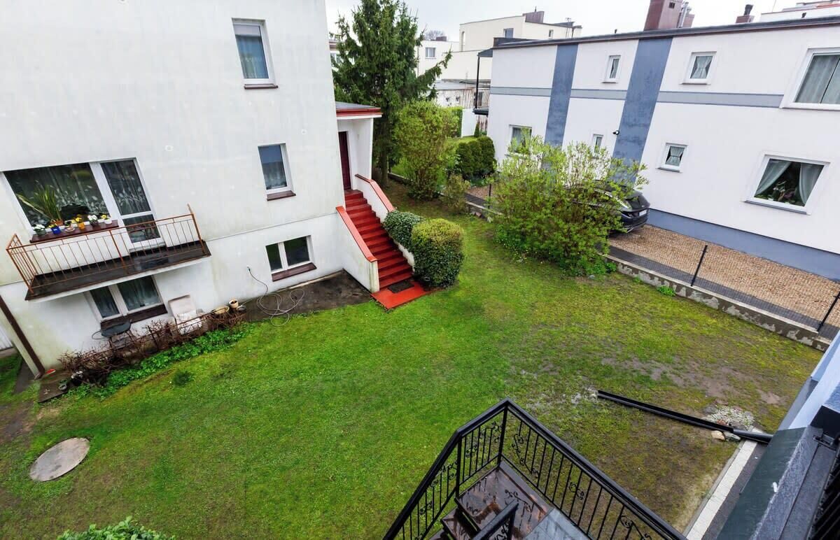 Un edifici residencial amb un jardí petit, una escala i un balcó.