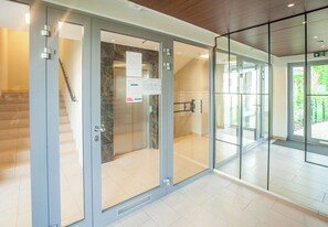 A modern building entrance with glass doors, a staircase, and a tiled floor. - Sopot City Comfort Apartment #1 (Sopot)