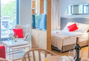 A hotel room with a bed, a sofa, a table with a bottle, and a chair. - Sopot City Comfort Apartment #1 (Sopot)