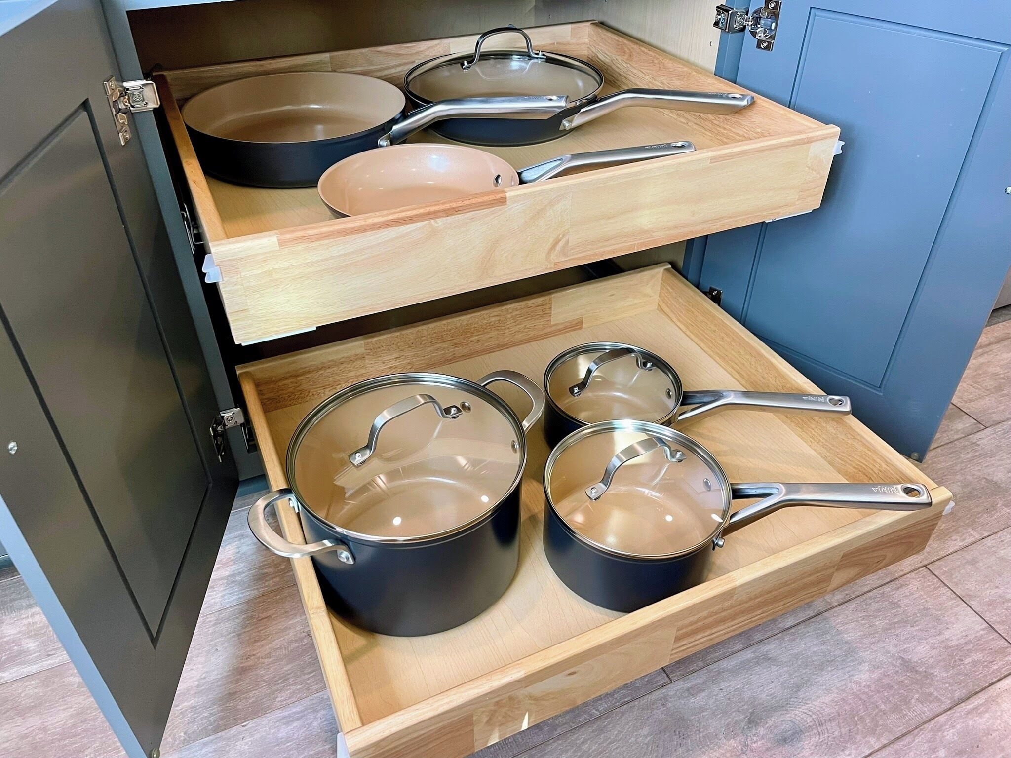 A kitchen with a wooden drawer organizer holding pots and pans.