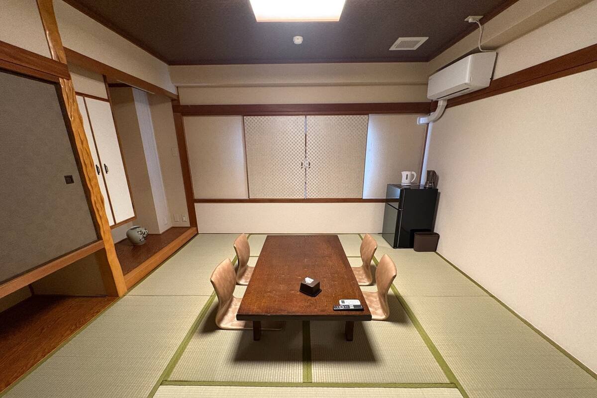 A conference room with tatami flooring, a wooden table, and chairs.