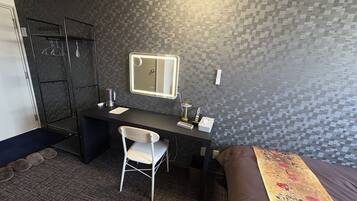 A hotel room with a desk, chair, bed, and a shower area.