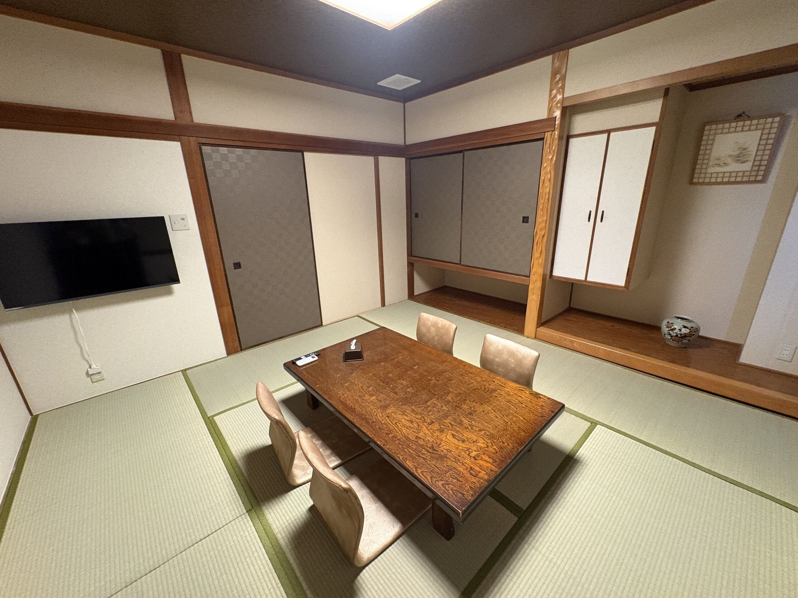 A traditional Japanese-style room with tatami flooring, a wooden table, and sliding doors.