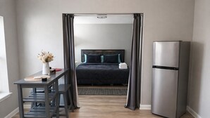 A modern hotel room with a bed, a desk, a refrigerator, and a view through a doorway. - Quiet Downtown Clermont Stay Near Waterfront Park (Clermont)