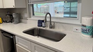 Une cuisine équipée d’un évier en acier inoxydable, d’une machine à café et d’un distributeur de papier toilette.