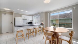 A modern kitchen with white cabinets, a central island with bar stools, and a dining table with chairs. - Seychelle unit 5 Kings Beach (Kings Beach)