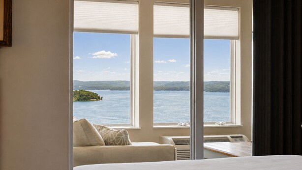 A hotel room with a bed, a table, and a view of a lake and island. - Lakeview 3BR/3BA Condo • Top Floor • Free Tickets (Branson)