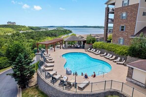 A swimming pool with lounge chairs and a gazebo, surrounded by a brick building with balconies. - Lakeview 3BR/3BA Condo • Top Floor • Free Tickets (Branson)