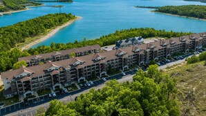 A multi-story hotel with a parking lot and a view of a large body of water. - Lakeview 3BR/3BA Condo • Top Floor • Free Tickets (Branson)