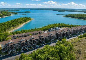 A multi-story hotel with a parking lot and a view of a large body of water. - Lakeview 3BR/3BA Condo • Top Floor • Free Tickets (Branson)