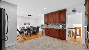 A modern kitchen with wooden cabinets, a tiled backsplash, and a dining area with a table and chairs.