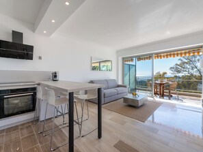 A modern kitchen with a dining area, a sofa, and a balcony with a view. - 1-Br Sea-View Apartment – Prestigious Residence – Parking (Vallauris)