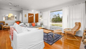 Una sala de estar moderna con un sofá, sillones, una mesa de centro y un amplio ventanal con cortinas.