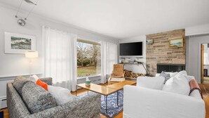 Una sala de estar moderna con chimenea, televisor y vistas al exterior.