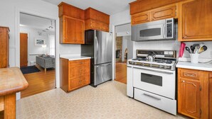Una cocina con armarios de madera, un refrigerador de acero inoxidable, un microondas y una estufa a gas.
