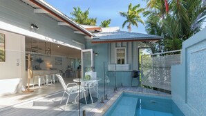 Ein modernes Haus mit Swimmingpool, Glastüren und einer Terrasse mit Gartenmöbeln.