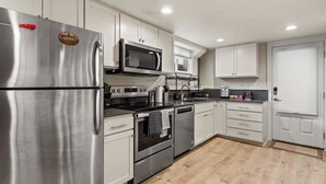 A modern kitchen with stainless steel appliances, white cabinetry, and a wooden floor. - Green Lake's 2B Lower Unit with Parking (Seattle)