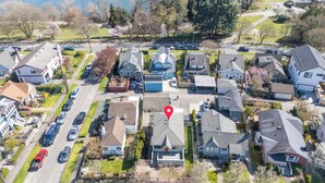 An aerial view of a residential area with houses, a parking lot, and a body of water in the background. - Green Lake's 2B Lower Unit with Parking (Seattle)
