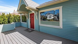 Een huis met een rode deur, een raam en een veranda.