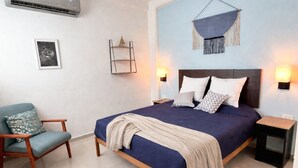 A bedroom with a bed, bedside tables, a chair, a hanging macrame piece, and a wall-mounted light fixture. - Bleu Balam • Quiet • Pool • Zazil-Ha • 1 Block to 5th Ave (Playa del Carmen)