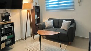 A modern living room with a sofa, a coffee machine, a lamp, and a bookshelf. - Bleu Balam • Quiet • Pool • Zazil-Ha • 1 Block to 5th Ave (Playa del Carmen)