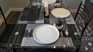 Una mesa de comedor preparada con platos, cubiertos y una computadora portátil.