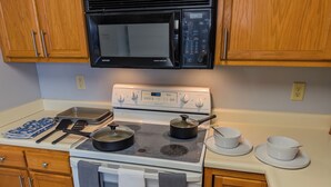 Una cocina con estufa, microondas y armarios de madera.