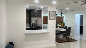 Una cucina moderna con elettrodomestici integrati, un'area pranzo con tavolo e sedie e una ventola a soffitto.