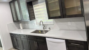 Una cucina moderna con mobili scuri, un lavello in acciaio inossidabile e una lavastoviglie.