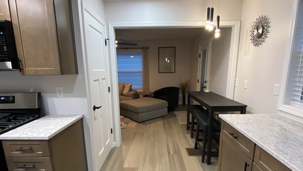 A modern kitchen with built-in appliances, a dining area with a bench, and a living space with a sofa and a wall-mounted clock. - Centrally located newly renovated 2  bungalow in Lafayette. (Lafayette)