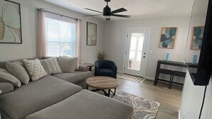 A living room with a sectional sofa, a round coffee table, a ceiling fan, and a dining area with a table and chairs. - Centrally located newly renovated 2  bungalow in Lafayette. (Lafayette)