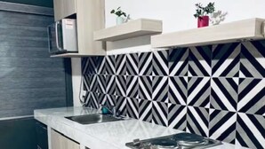 A kitchen with a white countertop, wooden cabinets, a microwave, and a patterned backsplash.