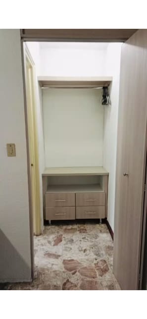 A room with a wardrobe, a small desk, and a stone-patterned floor.