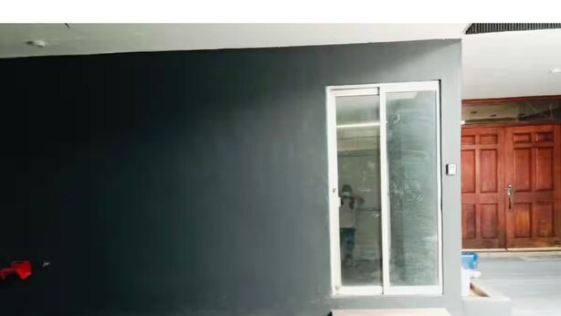 A garage with a dark wall, a sliding glass door, and a small wooden step leading to the door.