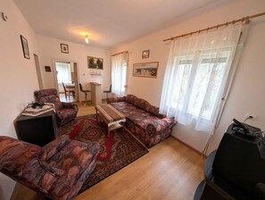 A living room with a sofa set, a coffee table, a TV, and a dining area with chairs and a table.