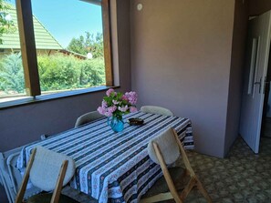 En balkong med ett bord, stolar och en vas med blommor.