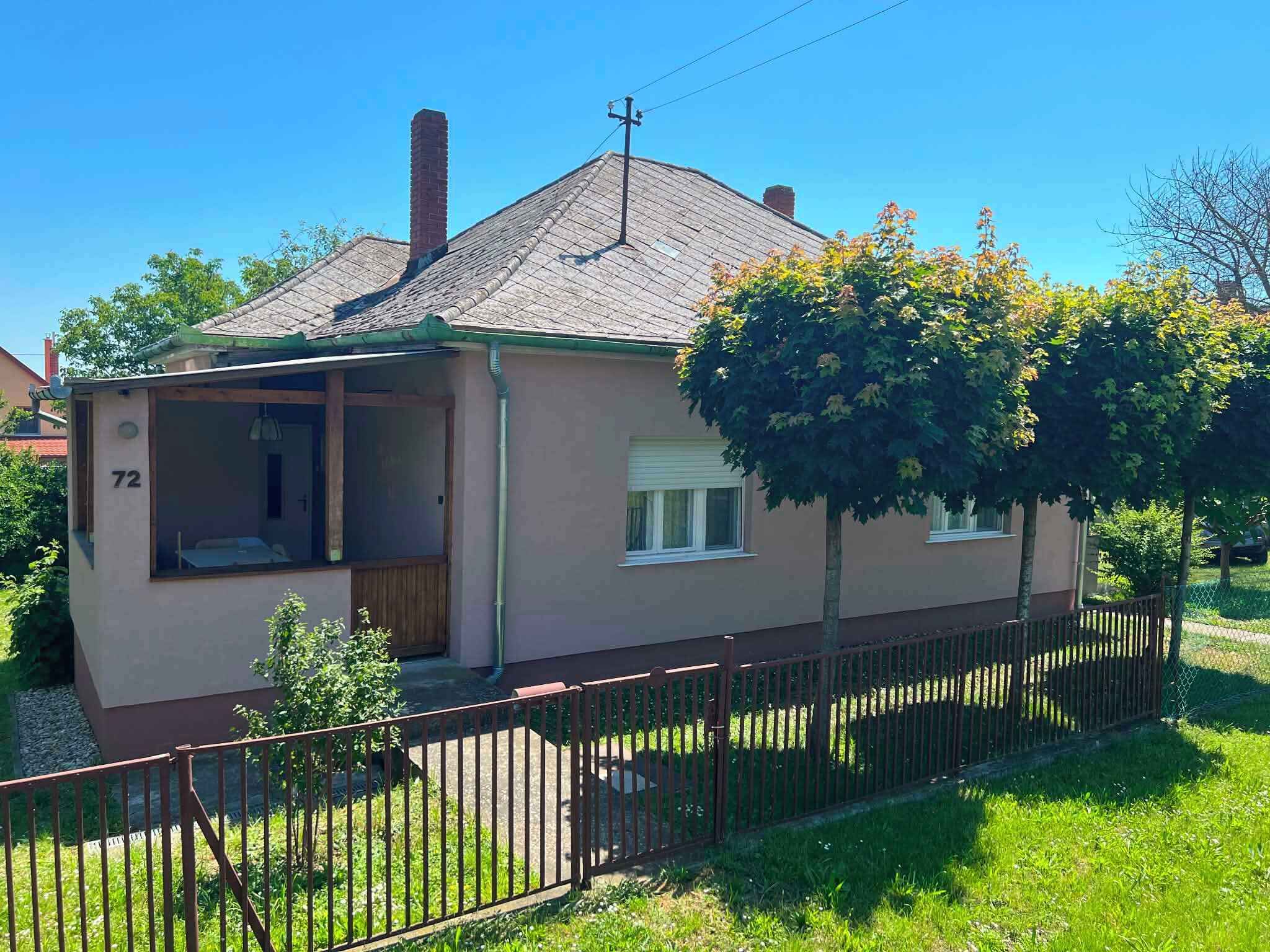 A single-story house with a porch, a chimney, and a number '72' on the side.