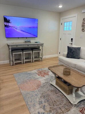 A living room with a flat-screen TV, a white sofa, a coffee table, and a patterned rug. - Full House • Walk to Beach • Families & Groups • Patio & Fire Pit • Parking (Myrtle Beach)