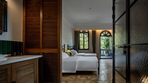 Une chambre avec un lit, une armoire en bois, une salle de bain avec un miroir et une vue sur l’extérieur.